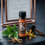 K Shot bottle with botanical elements on a dark surface